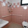 Bagno con piastrelle rosa, wc e doccia aperta.