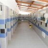 Corridoio di bagni pubblici con piastrelle a motivi blu e grigi e soffitto con travi in legno.