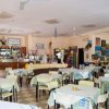 Interno di un ristorante con tavoli apparecchiati, un bancone e pareti decorate con quadri.