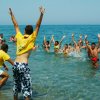 Persone che giocano e si divertono in mare, alcune indossano magliette gialle.