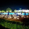Piscina illuminata di notte con ombrelloni blu.