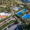 Complesso con campi da tennis, piscina e anfiteatro all'aperto circondato da colline e case.