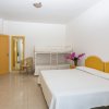 Camera con letto matrimoniale, letto a castello, armadio e sedia. Pareti bianche e mobili gialli.