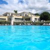 Piscina con bordo a sfioro davanti a un edificio moderno, cielo parzialmente nuvoloso.