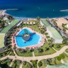 Vista aerea di un complesso con piscina a forma irregolare vicino al mare.
