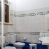 Bagno con piastrelle bianche e blu, WC e lavabo, finestra aperta.
