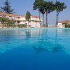 Piscina con acqua limpida, vari edifici e alberi sullo sfondo.