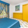 Camera con letto blu, armadio giallo, tende coordinate e pavimento decorato.