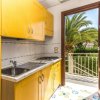 Cucina con mobili gialli, lavello e porta aperta verso un balcone con palme.