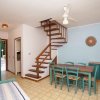 Soggiorno con tavolo, sedie, scala e ventaglio a soffitto.