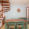 Sala da pranzo con scala in legno e tavolo con sedie verdi.