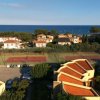 Vista dall'alto di case con tetti rossi, campi da tennis e mare.