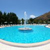 Piscina con fontana centrale e sdraio.