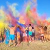 Festa all'aperto con polveri colorate lanciate in aria.