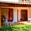 Una veranda esterna con tavolo apparecchiato, sedie bianche, barbecue e bicicletta.