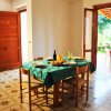 Sala da pranzo con tavolo apparecchiato, cucina e veranda esterna.