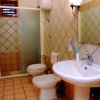 Un bagno con doccia, lavandino, bidet e WC. Rivestimento in piastrelle beige.