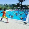 Piscina all'aperto con persone che fanno acquagym. Istruttore in primo piano.