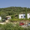 Due edifici bianchi con tetti marroni tra alberi e auto parcheggiate.