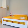 Camera da letto spaziosa con arredi bianchi e copriletto giallo.