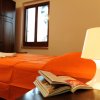 Camera con letto matrimoniale, copriletto arancione, lampada da tavolo e libro aperto.