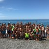 Gruppo di persone sulla spiaggia che festeggiano davanti al mare.