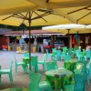 Tavolini verdi sotto ombrelloni gialli in uno spazio esterno con bar sullo sfondo.
