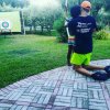 Persona aiuta un bambino a tirare con l'arco verso un bersaglio su un prato.