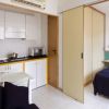 Cucina e area letto con parete divisoria scorrevole; tavolo, sedie e letto singolo sono presenti.