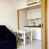 Piccola cucina con tavolo e quattro sedie pieghevoli bianche accanto a un divano scuro.