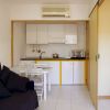 Spazio living con cucina moderna, tavolo da pranzo e divano scuro, evidenziato da pavimenti chiari.