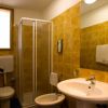 Bagno con piastrelle gialle, box doccia, lavabo e bidet.
