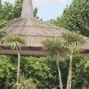 Tetto di paglia con alberi e piante verdi attorno.