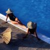 Due persone con cappelli di paglia siedono vicino a una piscina.