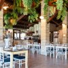 Interno di un ristorante con sedie bianche e piante pendenti.