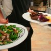 Cameriere serve piatti di carne e insalata.