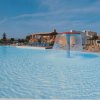 Piscina con getto d'acqua a fungo e lettini.