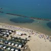 Spiaggia con ombrelloni colorati e mare calmo.
