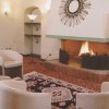 Un salotto con camino acceso, sedie bianche e tappeto decorato.