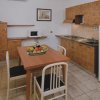 Cucina con tavolo da pranzo, quattro sedie, elettrodomestici e cestino di frutta.