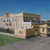Edificio giallo e bianco con cancello d'ingresso e cortile erboso.