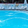 Piscina con sedie a sdraio e parete decorata.
