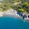Spiaggia con mare blu e piccola baia rocciosa, ombrelloni e un edificio.