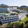 Resort bianco con piscine, circondato da colline verdi.