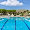 Piscina all'aperto circondata da ombrelloni e natura.