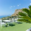 Terrazza con tavolo e sedie bianche, vista su una montagna e mare.