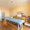 Sala massaggi con pareti colore pesca, due lettini coperti da teli blu e mobili in legno chiaro.