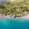Spiaggia vista dall'alto con mare e ombrelloni.