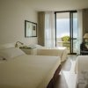 Camera d'hotel con tre letti e balcone.