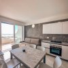 Cucina-soggiorno con tavolo, sedie, divano, cucina moderna e accesso al balcone.